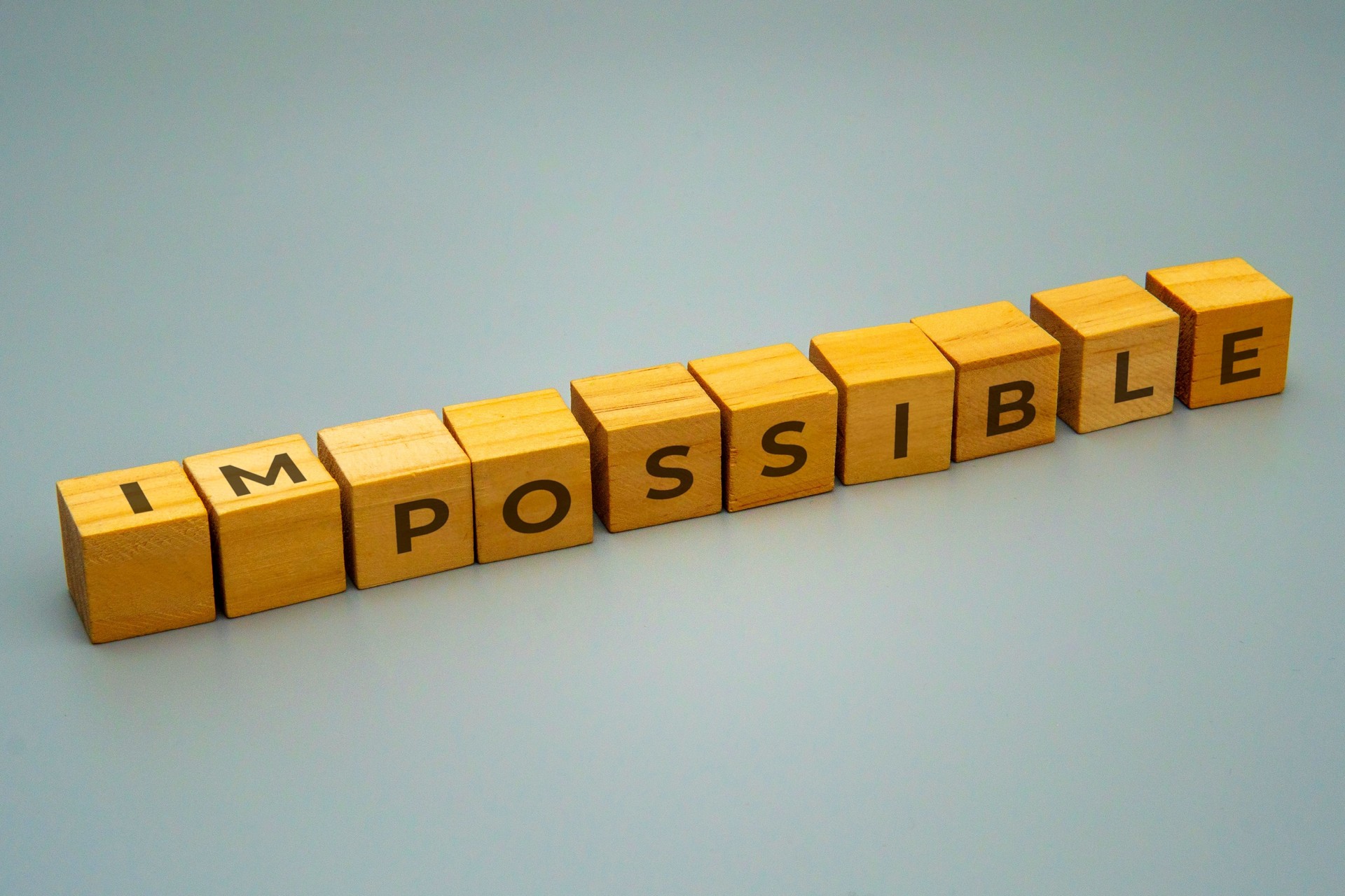 Blocks with the letters IMPOSSIBLE rearranged to spell POSSIBLE.